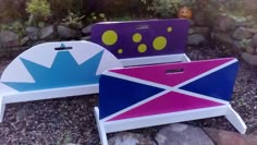 three children's chairs with different designs on them sitting next to each other in the grass