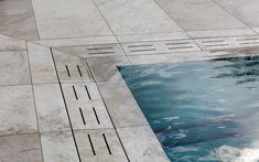 an empty swimming pool surrounded by tiled flooring