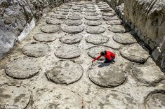 a person kneeling down on some rocks in the middle of an alley with lots of circles