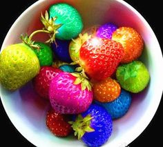 a white bowl filled with lots of different colored strawberries