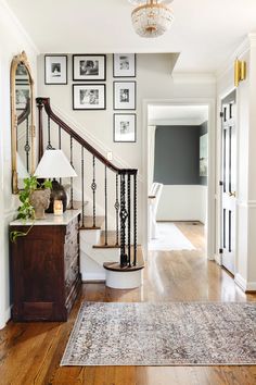 a staircase with pictures on the wall and a rug in front of it, along with a blue area rug