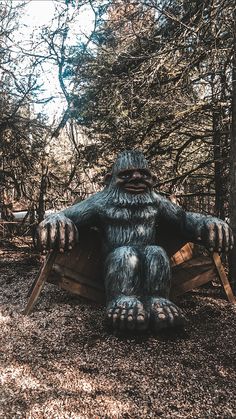 a statue of a bigfoot sitting in the woods