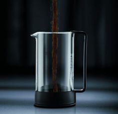 a coffee pot being filled with liquid from the bottom to the top, in front of a dark background