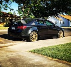 a black car parked on the side of a road next to a tree and grass