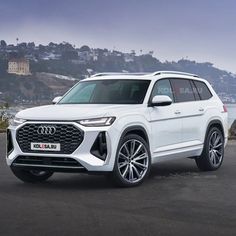 the new audi suv is parked in front of some water and hills with mountains in the background