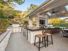 an outdoor kitchen with bar stools and grill