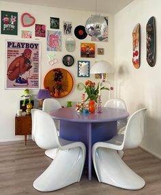 a dining room table with white chairs and pictures on the wall