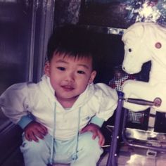 a young boy sitting next to a toy horse