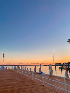 a wooden dock with boats in the water at sunset