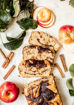 slices of apple cinnamon swirl bread sitting on top of a white surface next to apples and cinnamon sticks