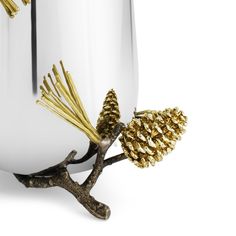 a gold pinecone is sitting on a branch in front of a white vase