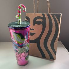 a starbucks cup with a candy cane in it next to a bag