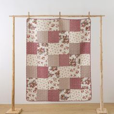 a red and white quilt hanging from a wooden frame