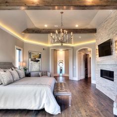 a bedroom with a large bed and fireplace in the corner, surrounded by wood flooring