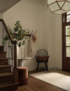 an entryway with a chair, coat rack and potted plant