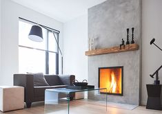 a living room filled with furniture and a fire place next to a large window on top of a hard wood floor