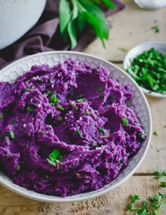 a bowl filled with purple mashed potatoes and garnished with parsley on the side