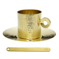 a cup and saucer on a plate with a metal spoon in front of it