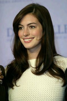 a woman with long brown hair smiling at the camera