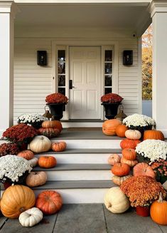 a front porch with pumpkins and flowers on the steps