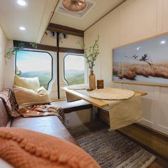 a living area with couch, table and large window in the back side of an rv