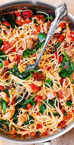 a skillet filled with pasta, meat and veggies on top of a wooden table