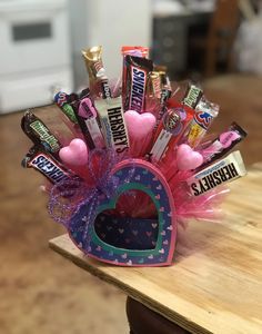 a heart shaped container filled with candy on top of a wooden table next to a counter