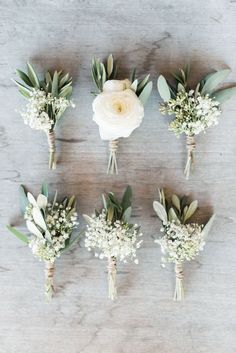 wedding flowers laid out on top of a wooden table with greenery and white blooms