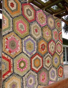 a large multicolored patchwork quilt hanging on the side of a wooden structure