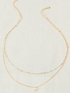 This delicate two-layer necklace features a dainty chain adorned with colorful painted dots, adding a playful touch to any ensemble. The second layer boasts a classic gold chain with a timeless pearl charm, creating an elegant and sophisticated contrast. Dainty Layering Necklaces With Pearl Chain, White Double Strand Pearl Necklace With Delicate Chain, Dainty Pearl Chain Necklace For Layering, White Double Strand Layered Necklace With Delicate Chain, Gold Delicate Chain Layered Necklace With Pearls, Dainty Yellow Gold Pearl Necklace With Delicate Chain, Dainty Double Strand Pearl Chain Layered Necklace, Dainty White Layered Pearl Chain Necklace, White Double Strand Pearl Chain Layered Necklace