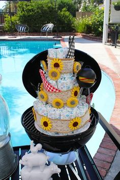 a cake sitting on top of a grill next to a pool with sunflowers