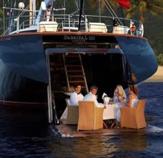 a group of people sitting at a table on top of a boat in the water