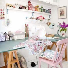 a sewing machine sitting on top of a table next to a pink chair and flower pot