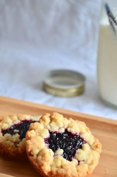 two blueberry pies on a cutting board next to a glass of milk