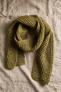 a green knitted scarf laying on top of a bed