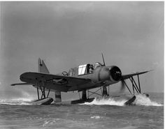 an old airplane is in the water with people on it's back and feet