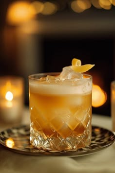 a glass filled with an alcoholic drink sitting on top of a table next to candles