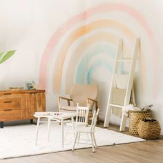 two chairs and a table in front of a wall with a rainbow painted on it