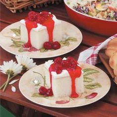 three plates with desserts on them sitting on a table next to flowers and bread