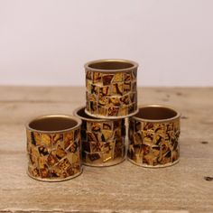 four metal cups sitting on top of a wooden table