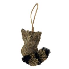 a small stuffed animal hanging from a string on a white background with a black and brown pom - pom tail