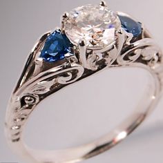 a white gold ring with two blue sapphires and an old - fashioned style diamond