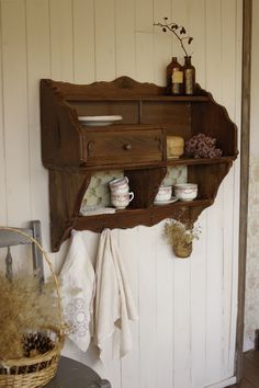 an old wooden shelf with dishes and cups on it in the corner of a room