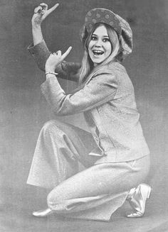 a woman is sitting on the ground with her hands in the air and smiling at the camera