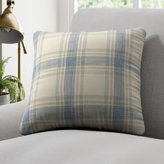 a white couch with a blue and beige plaid pillow sitting on it's side