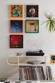 a record player sitting on top of a white table next to a wall with records