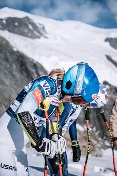 the skiers are bending down to adjust their skis on the snow covered mountain