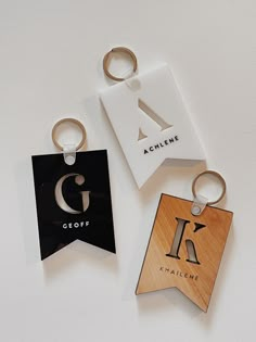 three wooden keychains with different logos on them