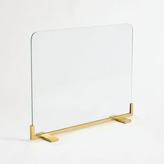 a glass and brass mirror on a white surface with a gold stand in the foreground