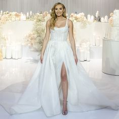 a woman in a white wedding dress standing next to a table with candles and flowers